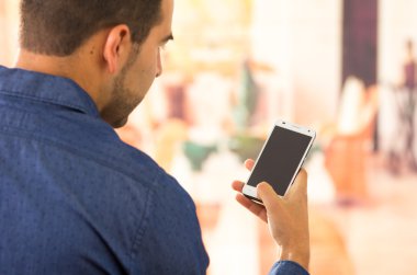 Attractive young man holding and reading a smartphone