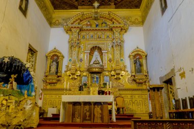 Heavily golden religious decorated alter inside San Diego church shot from front angle.