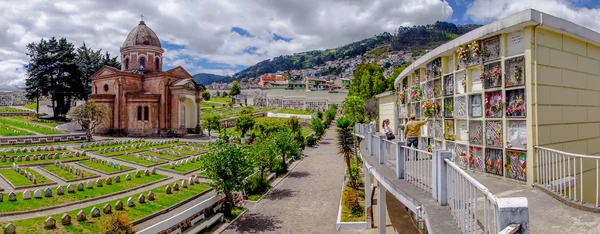 Panoramic view of San Diego church cemetary in Quito showing main building dome, tomb graves and gravestones with nice green garden including famous mountain Panecillo background — Stockfoto