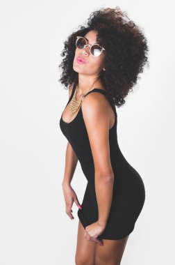 Hipanic model wearing black sexy dress, golden necklace, sunglasses and curly wild hair posing sensually from profile angle