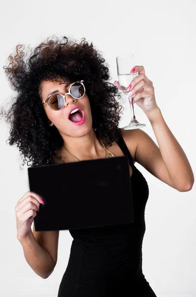 Modelo hispano vistiendo vestido sexy negro y gafas de sol sosteniendo tablero en blanco con el brazo derecho, copa de champán en otra mano brindando a la cámara —  Fotos de Stock