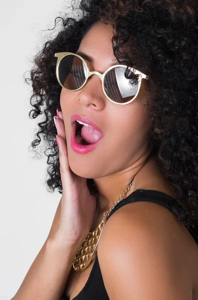 Hispanisches Model mit schwarzem sexy Kleid, goldener Halskette, Sonnenbrille und lockigem wildem Haar posiert sinnlich aus dem Profilwinkel — Stockfoto