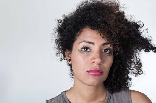 Cabeza hispana modelo morena con maquillaje desordenado y el pelo mirando infelizmente en la cámara, fondo blanco —  Fotos de Stock