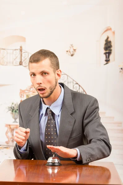 Upset guest customer ringing hotel bell at reception desk — Stock Photo, Image