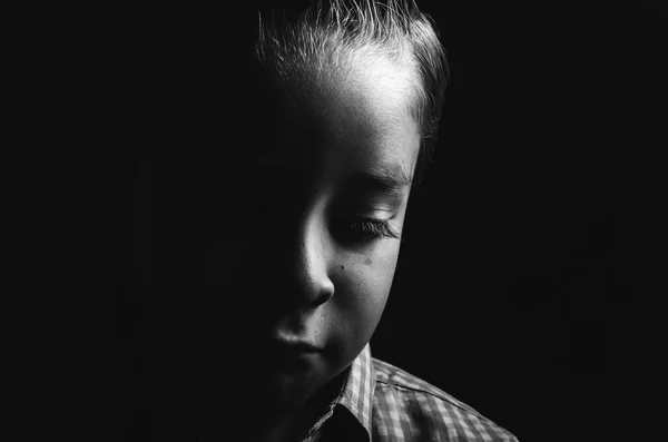 Svart og hvitt, lavt nøkkelportrett av en trist, liten gutt – stockfoto