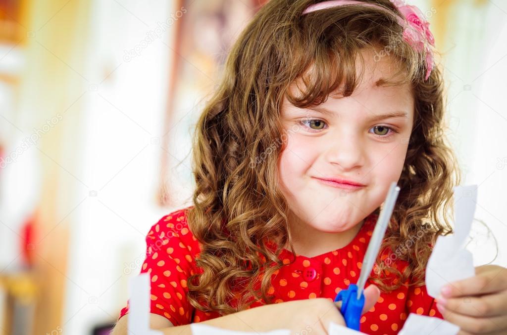 Cute girl cutting paper with scissors