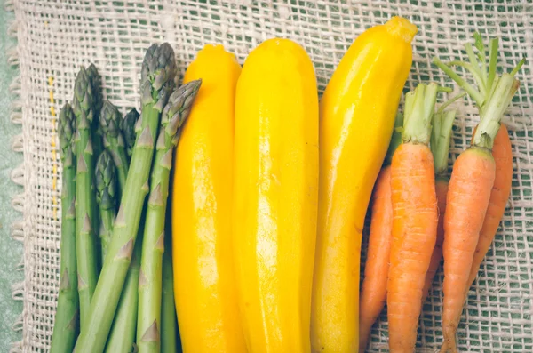 Bunch of brightly colored fresh asparagus, zucchinis and carrots in piles next to each other on a hemp cloth — Stock Image Bunch of brightly colored fresh asparagus, zucchinis and carrots in piles next to each other on a hemp cloth Stock Picture