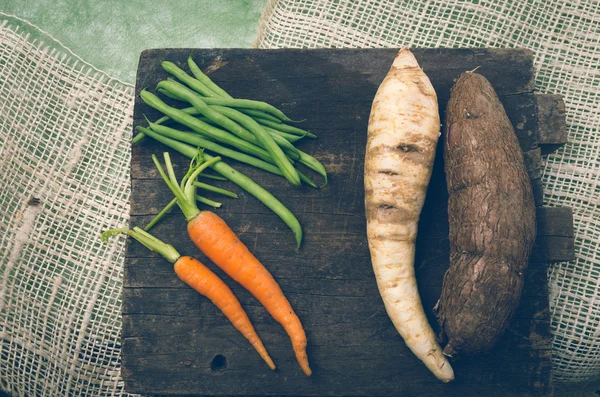 Deliziose carote, fagioli, carote bianche e patate dolci su legno — Foto Stock