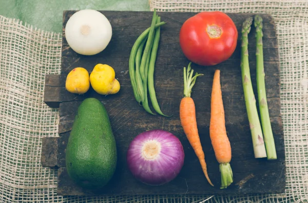 Aguacate natural, cebolla y zanahorias sobre tabla de madera . — Foto de Stock