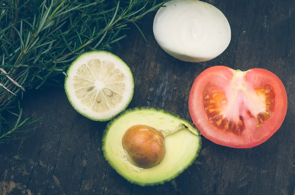 Rijp aromatische rozemarijn, lime, ui, avocado en tomaat gesneden in werd op een houten bord — Stockfoto