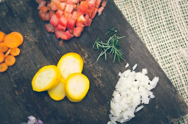 Pomodori tritati, cipolle, zucchine, carote e rosmarino su tavola di legno — Foto Stock