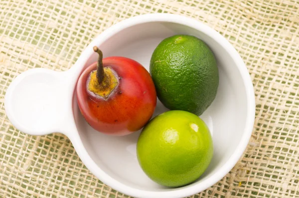 Aromatic garden-fresh tree tomato and limes in white bowl — Stock Photo, Image