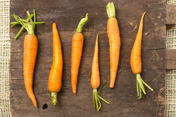 Carottes entièrement naturelles alignées sur une planche de bois — Photo