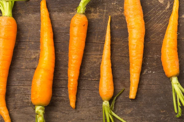 Carrots lined up on wooden board closeup — Stok fotoğraf