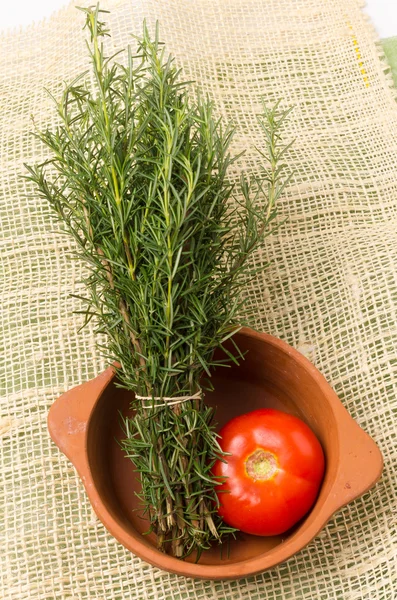 Organic delicious rosemary bundle and tomato inside caramic terracota bowl — Stock Photo, Image