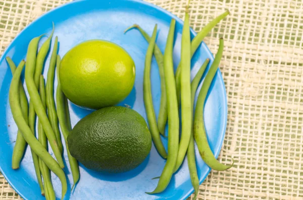 Kalk, avocado en groene bonen op blauw bord met rustieke achtergrond — Stockfoto