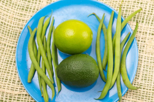 Kalk, avocado en groene bonen op blauw bord met rustieke achtergrond — Stockfoto