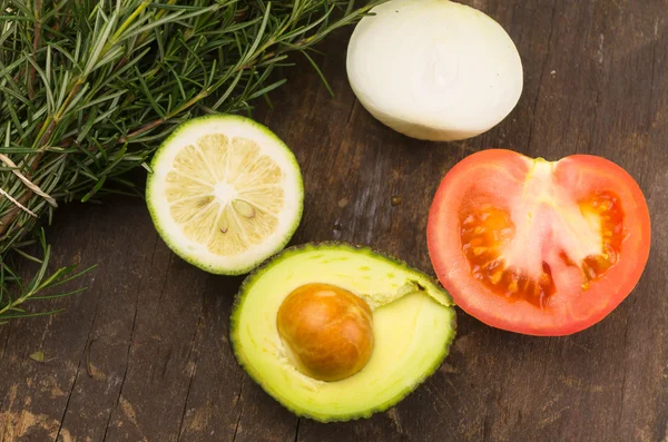 Rijp aromatische rozemarijn, lime, ui, avocado en tomaat gesneden in werd op een houten bord — Stockfoto