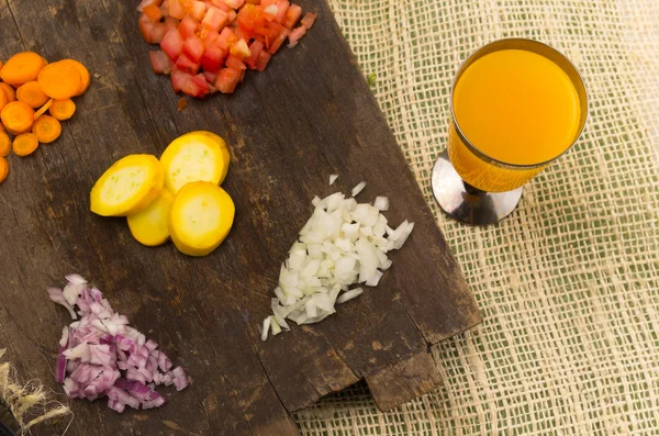 Pomodori tritati colorati, cipolle, zucchine, carote e rosmarino su tavola di legno — Foto Stock