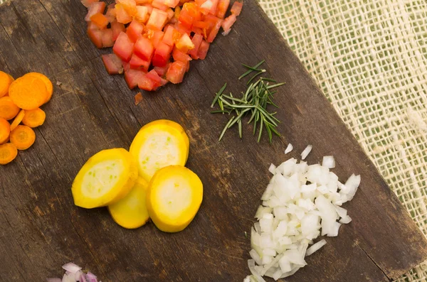 Pomodori tritati, cipolle, zucchine, carote e rosmarino su tavola di legno — Foto Stock