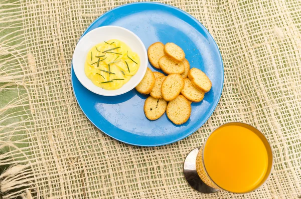 Blue plate with small slices of bread on it and butter rosemary next to orange juice — Stock Image Blue plate with small slices of bread on it and butter rosemary next to orange juice Royalty Free Stock Images