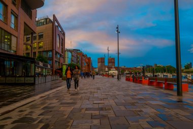 OSLO, NORWAY - 8 JULY, 2015: Popular Aker Brygge main pier during sunset hour, city hall visible in distance