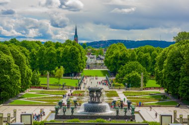 OSLO, NORWAY - 8 JULY, 2015: Big beautiful waterfall fountain located in Vigelandsparken sorrounded by charming pathways and green vegetation, shot from slightly above angle