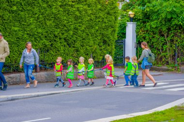 OSLO, NORWAY - 8 JULY, 2015: Group of kindergarden children walking on a line wearing reflect vests , headed for Vigelandsparken