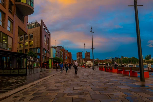 OSLO, NORWAY - 8 JULY, 2015: Popular Aker Brygge main pier during sunset hour, city hall visible in distance — Stock Fotó