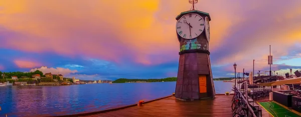 Oslo, norwegen - 8. juli 2015: charmanter kleiner uhrturm am aker brygge pier zur sonnenuntergangszeit — Stockfoto