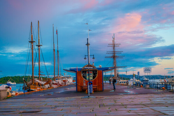 OSLO, NORWAY - 8 JULY, 2015: Charming marina area at Aker Brygge during sunset hour showing several mid-sized sailboats parked