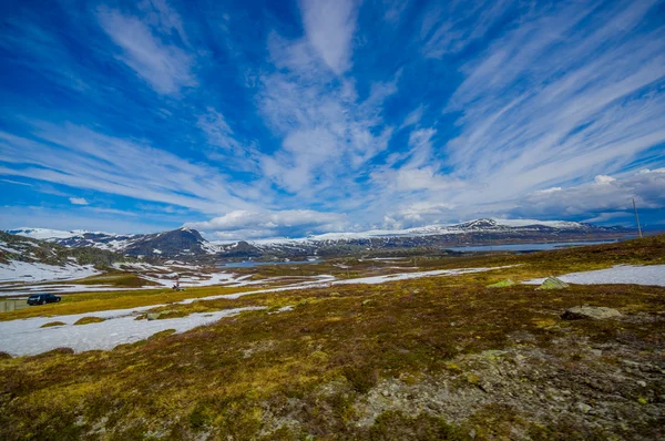 VALDRES, NORUEGA - 6 DE JULIO DE 2015: Impresionante naturaleza en Valdresflya, paisaje verde cubierto se extiende tan lejos como la vista puede ver con manchas de nieve y lagos bajo el hermoso cielo azul — Foto de Stock