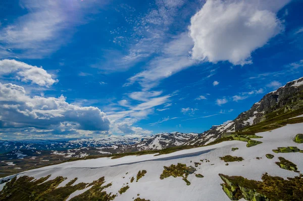ヴァルドレス, ノルウェー - 2015 年 7 月 6 日: 雪と美しい青空の下で湖の観光スポットを見渡す限りに広がって美しい自然 Valdresflya、緑に覆われた風景 — ストック写真