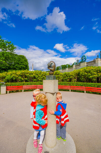 OSLO, NORWAY - 8 ИЮЛЯ, 2015: Gravel plaza in Vigelandsparken with red benches sorrounded by green bushes
