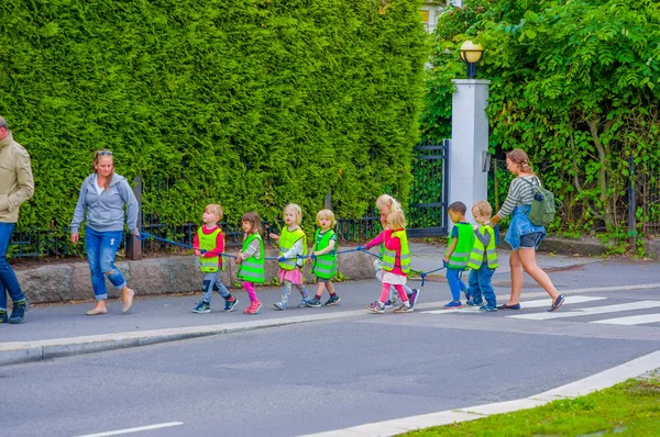 OSLO, NORUEGA - 8 JULHO, 2015: Grupo de crianças jardim de infância andando em uma linha vestindo refletem coletes, indo para Vigelandsparken — Fotografia de Stock