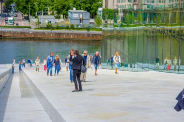 OSLO, NORWAY - 8 JULY, 2015: People walking on the roof of famous spectacular opera building located waterfront