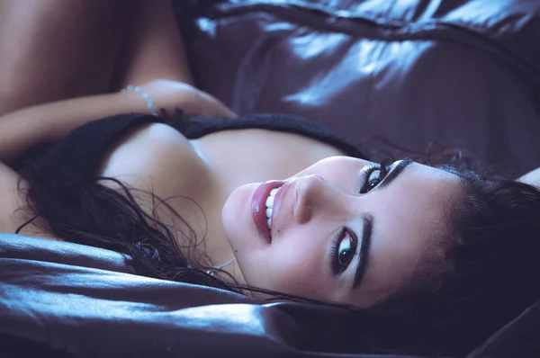 Sexy latina model lying in seductive position revealing some skin and looking into camera from above her head — Stock Fotó