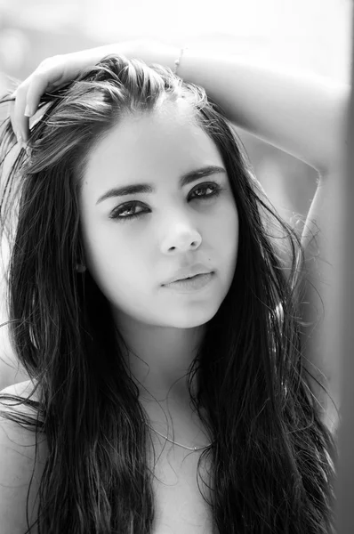 Beautiful headshot of latina model looking into camera with seductive dark eyes from side angle black and white edition — ストック写真