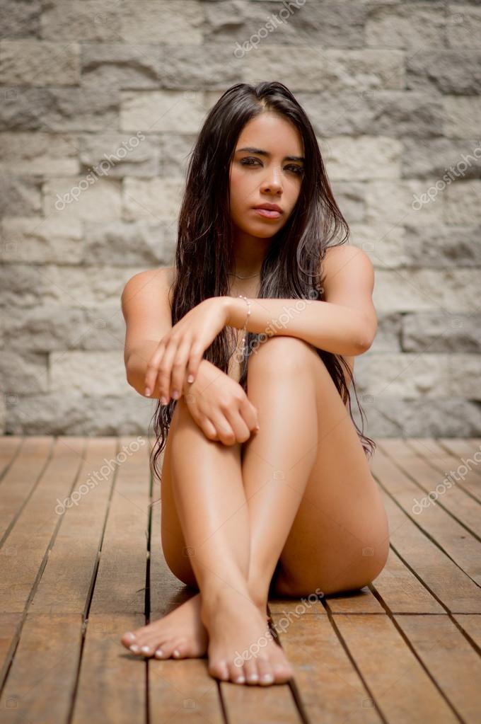 Sexy latina model sitting naked on wooden floor facing camera with legs and  arms crossed covering up artistically in front of grey brick wall Stock  Photo by Â©pxhidalgo 82573824