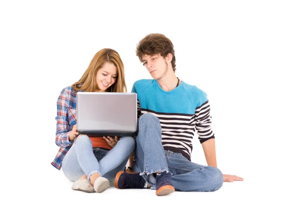 Portrait of attractive young happy couple in love man and woman isolated over white background sitting on floor looking to computer. — Stockfoto