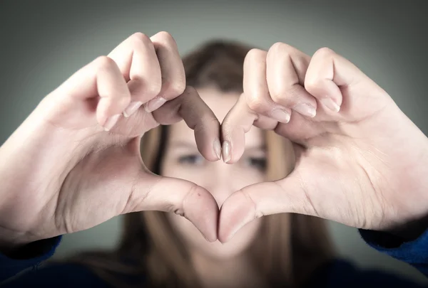 Närbild porträtt av söt ung tonåring tjej att göra ett hjärta med fingrarna — Stockfoto