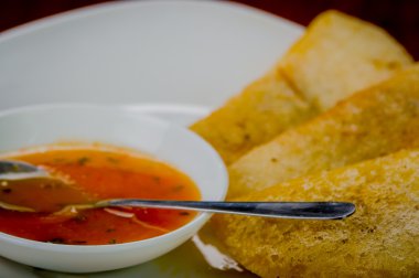 Beyaz plaka dizilmiş üç lezzetli empanadas ve küçük kase üstte kırmızı salsa ile