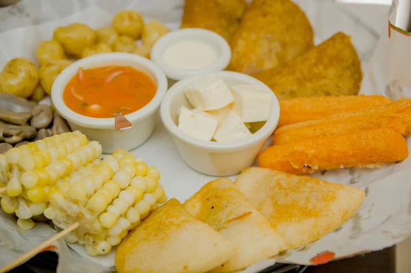 Closeup delicious food platter of typical latin foods such as corn, empanadas, abbas, cheese and salsas nicely arranged — Stock Photo, Image