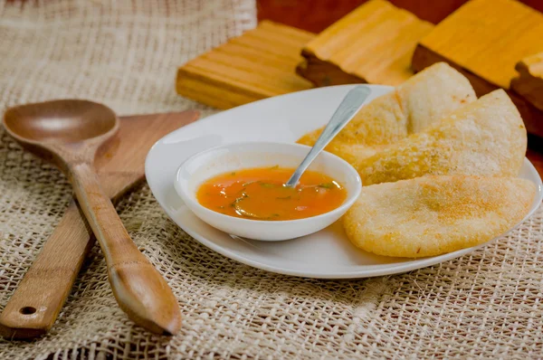 Three empanadas nicely arranged on white platter next to small salsa bowl and rustic background — Stock Photo, Image