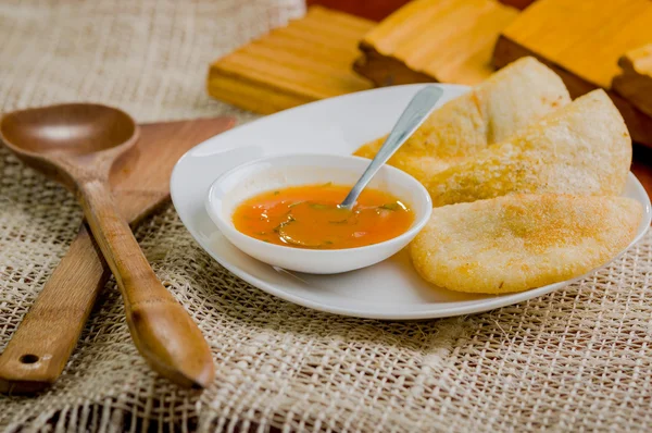 Three empanadas nicely arranged on white platter next to small salsa bowl and rustic background — Stock Photo, Image