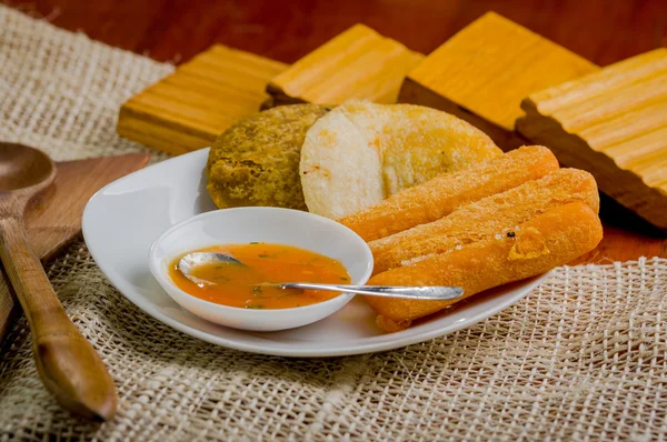 Close-up de prato branco misto com alimentos típicos fritos latinos. abbas, queijo e salsa tigela delicadamente arranjado cenário rústico — Fotografia de Stock