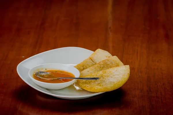 Piatto bianco con tre deliziose empanadas allineate e piccola ciotola di salsa rossa in cima — Foto Stock