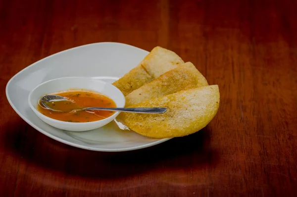 Assiette blanche avec trois empanadas délicieux alignés et petit bol de salsa rouge sur le dessus — Photo