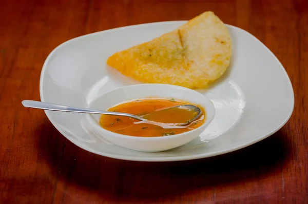 Empanada deliciosa colocada em placa branca com pequena tigela de salsa — Fotografia de Stock