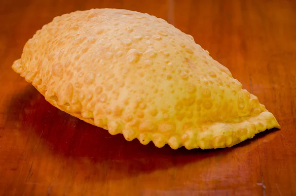 Large fluffy empanada beautiful color lying on wooden surface — Stock Photo, Image